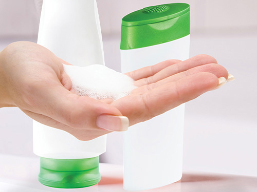Image of lotion, body wash, or shampoo bottles, and a hand holding product