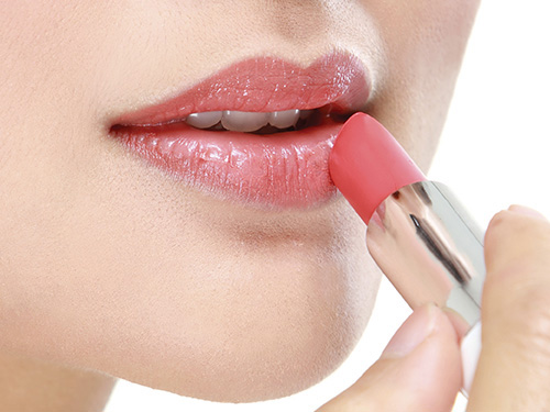 Close up image of woman applying lipstick color to her lips